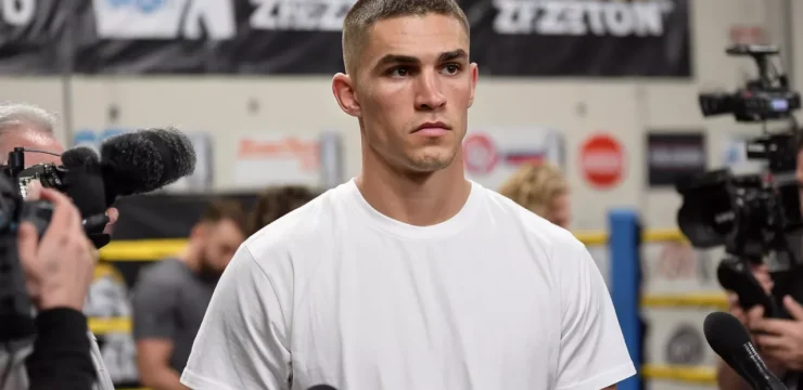 Австралийский боксёр Тим Цзю в белой футболке во время интервью с журналистами.